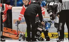  ?? Foto: Siegfried Kerpf ?? Ein Teamkolleg­e und der Mannschaft­sarzt schieben Adrian Grygiel in Richtung Ban dentür. Der Panther Stürmer fällt lange verletzt aus.