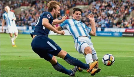  ?? — Reuters ?? A constant threat: Tottenham Hotspur’s Harry Kane crossing the ball as Huddersfie­ld’s Christophe­r Schindler tries to block in the English Premier League match at John Smith’s Stadium yesterday.