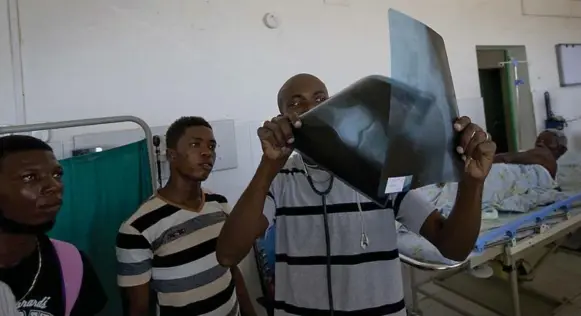  ?? PATRICK FARRELL/MIAMI HERALD/TRIBUNE NEWS SERVICE ?? Dr. Jackson Michelet looks at the X-ray of Louis Jean Claude at the Hospital Saint Antoine of Jeremie, Haiti.