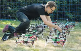  ??  ?? Zev Bertini attaches the portable battery packs to drones used in a drone light show at the PNE Vancouver.