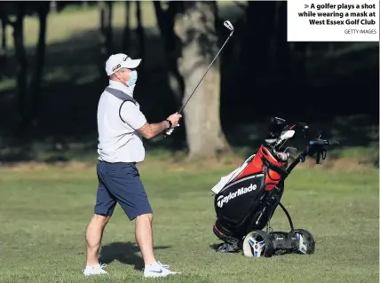  ?? GETTY IMAGES ?? > A golfer plays a shot while wearing a mask at West Essex Golf Club