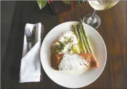  ??  ?? Cajun salmon, pan-seared and topped with house-made lemon butter cream sauce, is served with jalapeno mashed potatoes and sauteed vegetables.