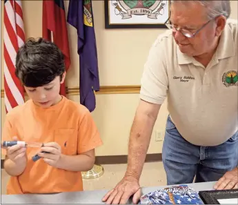  ?? Kevin Myrick/ Standard Journal ?? Aragon’s Maddox Guice shows off the variety of items he uses to control his Type 1 diabetes to Mayor Garry Baldwin following a brief ceremony where Maddox was provided with a proclamati­on honoring him and others suffering from Juvenile diabestes.