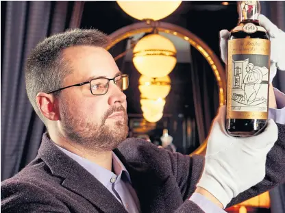  ?? Picture: Peter Dibdin. ?? Whisky Auctioneer director Iain Mcclune inspects a rare bottle.