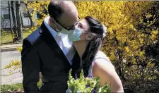  ?? (MICHAEL WARGO VIA AP) ?? In this April 11, 2020, photo provided by Michael Wargo, newlyweds Danielle Cartaxo and Ryan Cignarella kiss while wearing masks after getting married in West Orange, N.J.