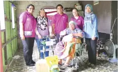  ??  ?? Nurhazimah (far right) and KPJ staff present a wheelchair to a recipient from Kampung Tiang Api.