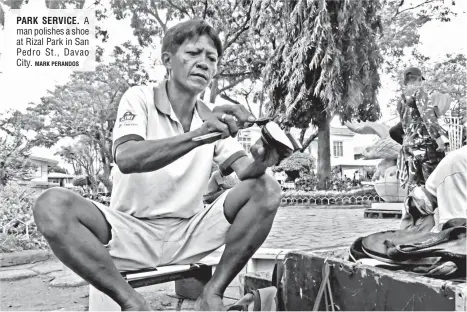  ?? MARK PERANDOS ?? PARK SERVICE. A man polishes a shoe at Rizal Park in San Pedro St., Davao City.