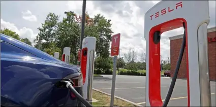  ?? AP PHOTO/CHUCK BURTON ?? In this July 19 photo a Tesla vehicle charges at a Tesla Supercharg­er site in Charlotte, N.C.