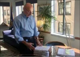  ?? JULIET LINDERMAN — THE ASSOCIATED PRESS ?? In this photo, Mark Robbins, the last remaining member of the Merit Systems Protection Board, looks through stacks of legal cases piled up on his desk in his Washington office.