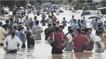  ??  ?? 0 Residents wade through a flooded road in Honduras ( AP Photo/ Delmer Martinez)