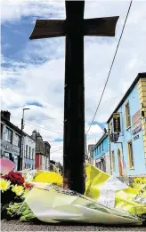  ?? PHOTOS: GERRY MOONEY/MARK CONDREN ?? Shrine:
Flowers and a cross at the spot where the garda was killed in Castlerea; and, above left, retired garda and neighbour Brian Colleran, who also served with Colm, watches the Mass with Garda Noel Gibbons, Breda Colleran and Dympna Geoghegan.