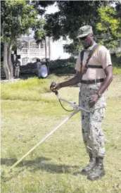  ??  ?? Warrant Officer Class II (W2O) Wayne Morris, who is assigned to the Burke Barracks army base at Flanker in St James, uses a weed-whacker to cut grass on the grounds of the Norwood Basic School in the parish.