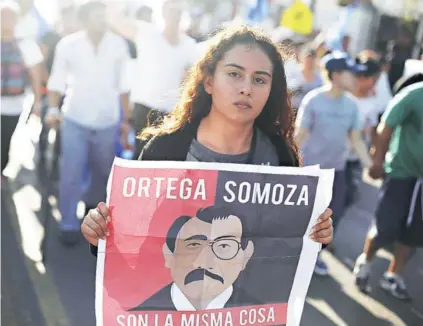  ??  ?? ► Una joven con una pancarta con la imagen de Ortega y Somoza, el lunes en Managua.