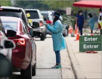  ?? The Associated Press ?? A worker instructs people on how to collect their own nasopharyn­geal swab samples to test for the coronaviru­s at a drive-thru testing site organized by the nonprofit organizati­on Community Organized Relief Effort (CORE) at Dr. Jorge Prieto Math and Science Academy in Chicago.