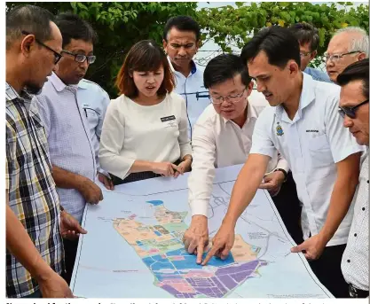  ??  ?? New school for the people: Chow (fourth from left) and Goh pointing to the location of the site on a map plan while briefing Mohd Bazid (second left) and Teo (third from left) on where the proposed school will be built in Batu Kawan.