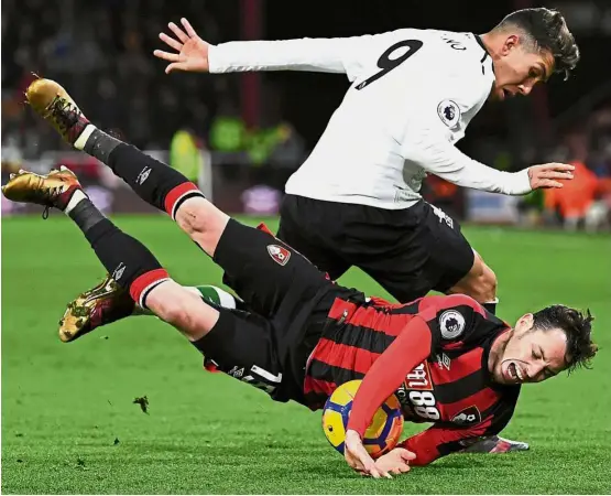  ?? — Reuters ?? Are you OK?: Liverpool’s Roberto Firmino colliding with Bournemout­h’s Adam Smith in the English Premier League match at the Vitality Stadium on Sunday. Liverpool won 4- 0.