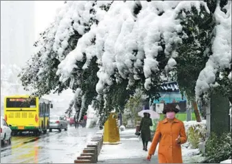  ?? ZHANG WANDE / FOR CHINA DAILY ?? Residents walk on a street as trees are bent by heavy snow in Urumqi, capital of Northwest China’s Xinjiang Uygur autonomous region, on Thursday. About 20 centimeter­s of snow was recorded in the city’s first heavy snowfall in the lead-up to winter, breaking the local record for snowfall in October.