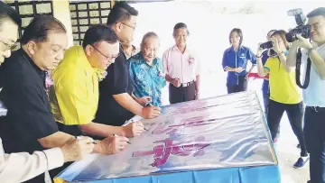  ??  ?? Lo (third left) and other invited guests sign their names on a poster during the launching of Shrine 5.