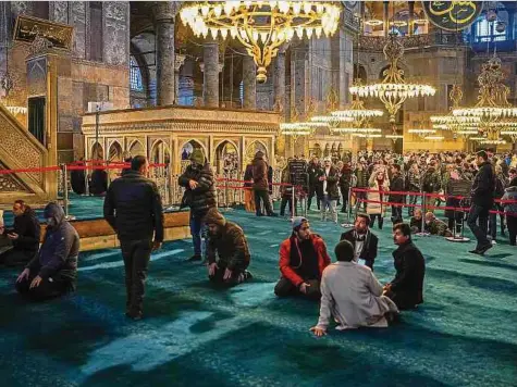  ?? Foto: dpa ?? Muslime beten im linken Bereich der Hagia Sophia, während Touristen das Museum auf der rechten Seite besuchen.