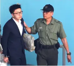  ??  ?? Leung is held by a correction­al services department officer inside a detention centre before leaving for the High Court for a sentencing hearing. — Reuters photo