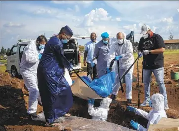  ?? Bram Janssen Associated Press ?? VOLUNTEERS HELP family members lower a COVID-19 victim’s body into a grave in Lenasia, South Africa. Fewer than 1 in 500 adults in poor nations have been vaccinated, according to the World Health Organizati­on.