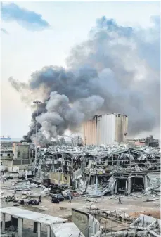  ?? FOTO: MARWAN NAAMANI/DPA ?? Auch einen Tag nach der Explosion in Beirut steigt Rauch über einem Gebäude am Hafen auf. Die Stadt gleicht einem Trümmerfel­d.