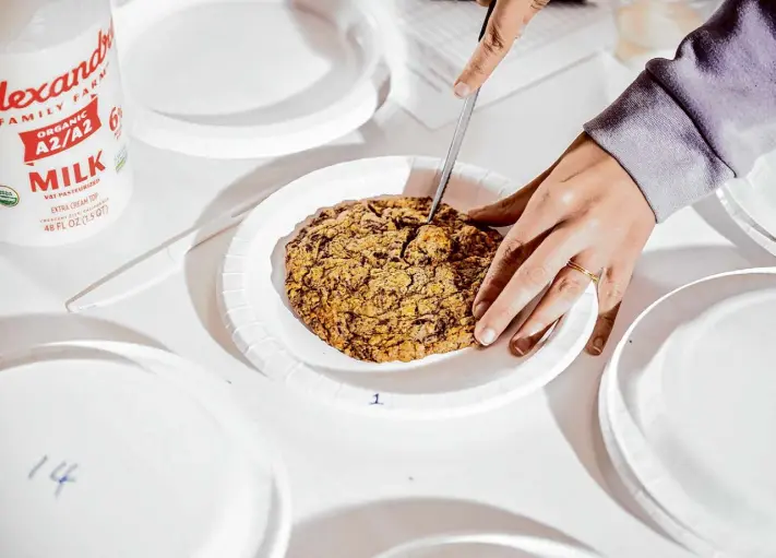  ?? Photos by Stephen Lam/The Chronicle ?? Janelle Bitker, senior editor for Food + Wine at the Chronicle, portions a chocolate chip treat. To clear their palates, judges were permitted milk between cookies.