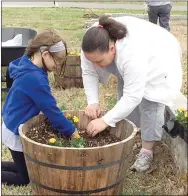  ??  ?? Laura Goddard and her daughter, Riley, 10, plant flowers in a barrel at the Prairie Grove community garden, located across from Prairie Grove Senior Center.