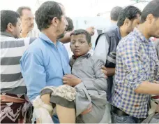  ?? — Reuters ?? A Yemeni man holds a boy who was injured by an airstrike in Saada.