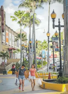  ??  ?? Tourists walk along a shopping area Wednesday in Tamuning, Guam.