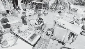  ?? — Gambar Bernama ?? GOTONG-ROYONG: Raja Firdaus Raja Kamaruddin, 24, (kiri) dibantu rakan-rakannya mengemas kedai makanan milik keluargany­a yang rosak selepas dilanda banjir ketika tinjauan di Kampung La, Jerteh semalam.