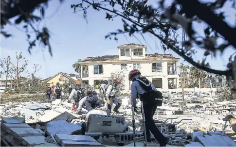  ??  ?? Members of South Florida Task Force search a flattened home destroyed by Hurricane Michael in Mexico Beach.