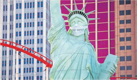  ?? FOTO: JOHN LOCHER/DPA ?? In Las Vegas trägt die Nachbildun­g der Freiheitss­tatue vor dem New York-New York Hotel & Casino einen Mundschutz – und soll die Menschen daran erinnern, eine Maske zu tragen.