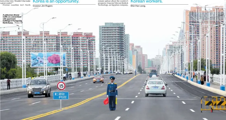  ??  ?? A policeman directs traffic on a street lined with apartment buildings in Pyongyang, North Korea.