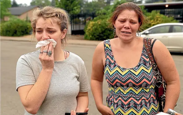  ?? AP ?? Sherry Bledsoe, left, cries next to her sister, Carla, outside the sheriff’s office after hearing news yesterday that Sherry’s children, James and Emily, and grandmothe­r, Melody Bledsoe, were killed in a wildfire.