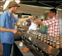  ??  ?? Keegan Smith, left, makes a purchase from Walter Warner of Potlicker Kitchen at the Saratoga Balloon and Craft Festival.