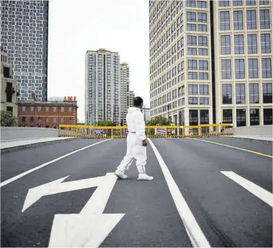  ?? Aly Song / Reuters ?? Un trabajador con traje protector en una calle de la ciudad de Shanghái, totalmente confinada.