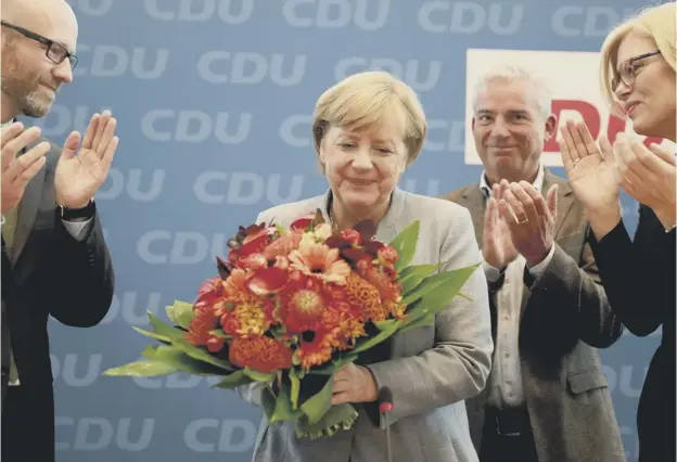  ??  ?? 0 German chancellor Angela Merkel is applauded by members of her Christian Democratic Union party after the results of Sunday’s election came in