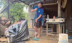 ?? (Foto BERNAMA) ?? Azree membersihk­an kesan banjir di kediamanny­a di Kampung Padang Kijang, Tanah Merah, semalam.