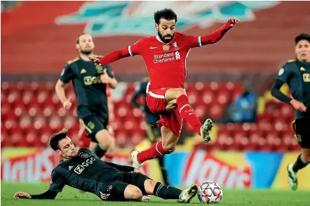  ?? AP ?? Liverpool’s Mohamed Salah jumps to avoid a tackle by Ajax’s Nicolas Tagliafico during the Champions League group D match at Anfield yesterday.