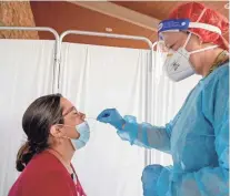  ?? CHRIS LANDSBERGE­R/THE OKLAHOMAN ?? Shannon Livsey receives a COVID-19 test from registered nurse Dasha Johnson on Aug. 4 during an employee testing event at the Absentee Shawnee Tribe’s Little Axe Health Center in Norman. The clinic requires frequent testing among employees who are not vaccinated.