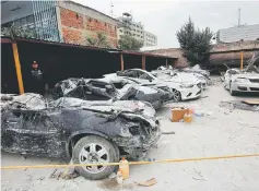  ??  ?? A police officer stands next to cars destroyed in an earthquake. — Reuters photo