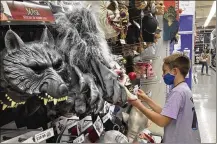  ?? AP ?? A customer checks out a Halloween mask in Miami. Americans continued to spend at a solid clip in September despite rising prices and snarled global supply chains that limit the flow of goods.
