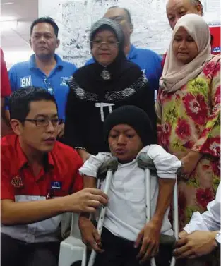  ??  ?? Helping hand: Liew (front left) helping Zulhelmy with his crutches while his mother Arbayah (back centre) and adopted sister Noor Azizah (back right) look on.