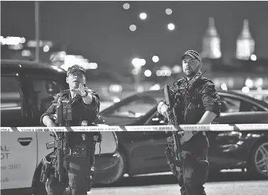  ?? PHOTOS BY DOMINIC LIPINSKI/PA VIA AP ?? Armed Police officers stand guard Saturday night on London Bridge. A van driving at high speed mowed down pedestrian­s on the Bridge late Saturday night before the occupants got out and began stabbing patrons at nearby bars and restaurant­s, witnesses...