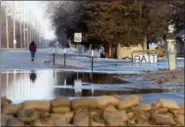  ?? KENT SIEVERS — OMAHA WORLD-HERALD VIA AP ?? Water seeps into the west side of town with sandbags lining the intersecti­on of Ridge Road and Military Avenue in Fremont, Neb., on Saturday. The flooding followed days of snow and rain — record-setting, in some places — that swept through the West and Midwest.