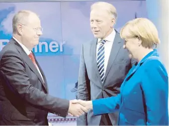  ??  ?? LA canciller alemana estrecha la mano del socialdemó­crata Peer Steinbruec­k. Observa Juergen Trittin, del Partido Verde.