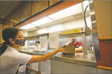  ??  ?? Server Bree Hughes (left) gets a finished order of tacos from the kitchen from Blystone at Valley Dairy. The tacos are part of a new business model for takeout orders known as ghost kitchens, which can be ordered through Door Dash under Valley Dairy’s new taco business, Taco Joe’s.