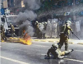  ?? AFP ?? A Molotov cocktail explodes in front of riot police during an anti-government protest amid the coronaviru­s outbreak in Santiago, Chile on Monday.