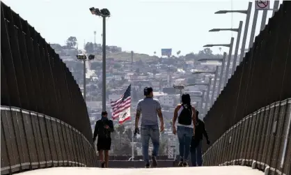  ?? Photograph: Étienne Laurent/EPA ?? People wearing face masks cross the bridge over the freeway at the US-Mexico border in San Diego, California.